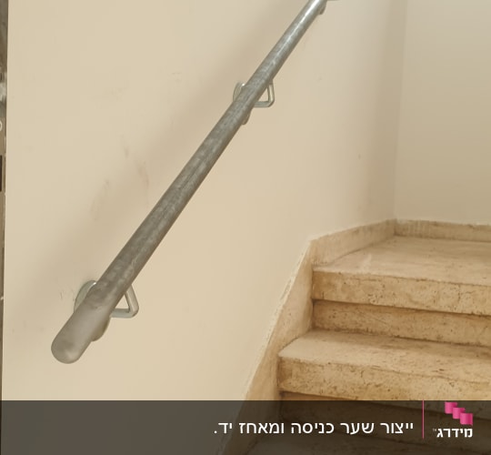 מעקה מתכת צמוד לקיר מעל מדרגות אבן